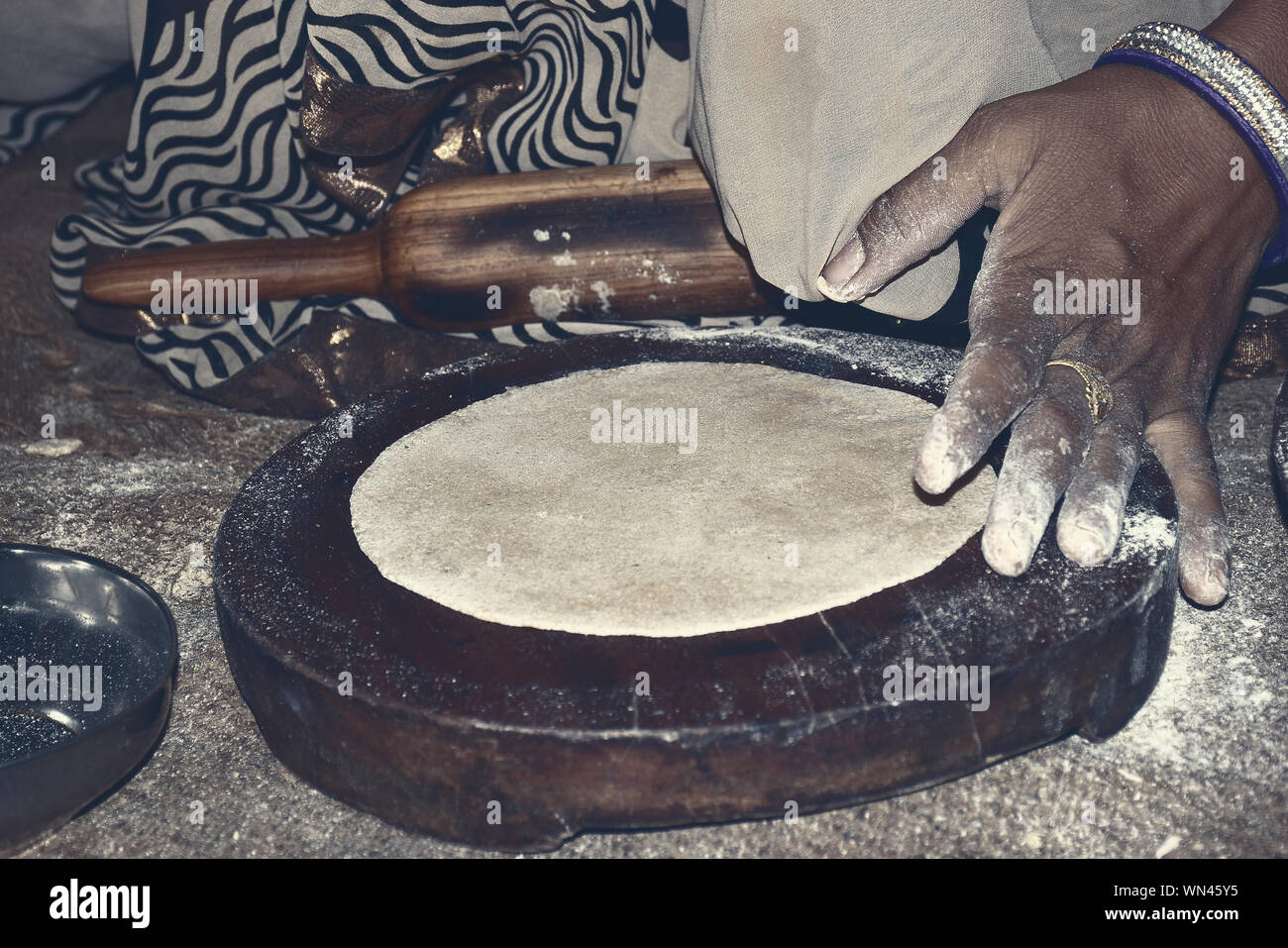 indian women handling bread with indian cylinder of wood Stock Photo