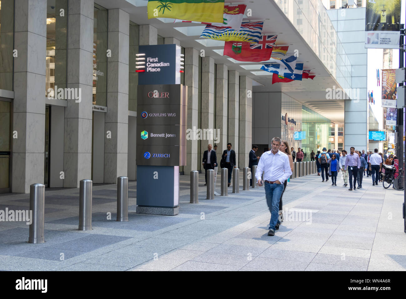 People walk by the entrance of  First Canadian Place in Toronto's Financial District. Stock Photo