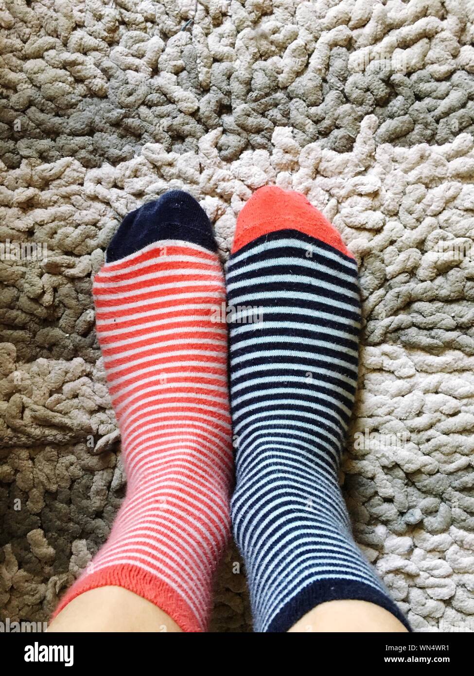 Cropped Image Of Woman Wearing Different Socks On Carpet Stock Photo - Alamy