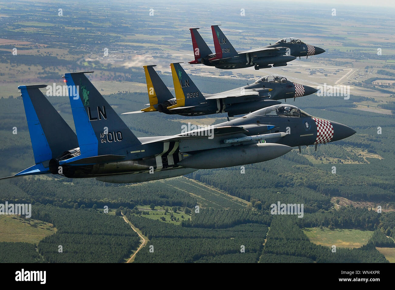Two F-15E Strike Eagles and an F-15C Eagle assigned to the 48th Fighter Wing painted with their respective squadron heritage color scheme conduct aerial maneuvers over Royal Air Force Lakenheath, England Sept. 3, 2019. The Liberty Wing conducts routine training daily to ensure the 48th Fighter Wing brings unique air combat capabilities to the fight when called upon by United States Air Forces in Europe-Air Forces Africa. (U.S. Air Force photo/ Tech. Sgt. Matthew Plew) Stock Photo