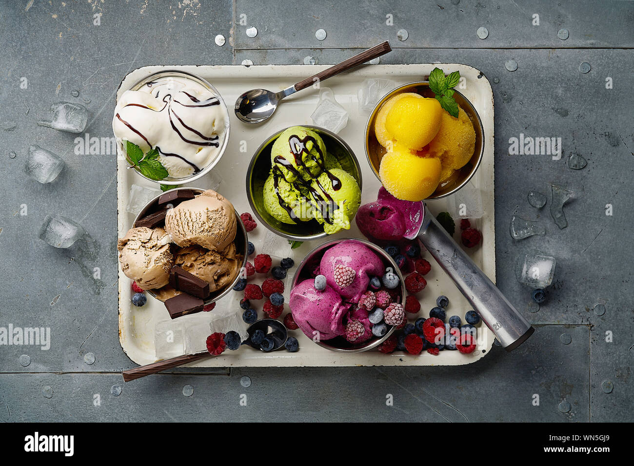 Assorted flavors and colors of gourmet Italian ice cream served on steel table. Mango, chocolate, green matcha ice cream Stock Photo