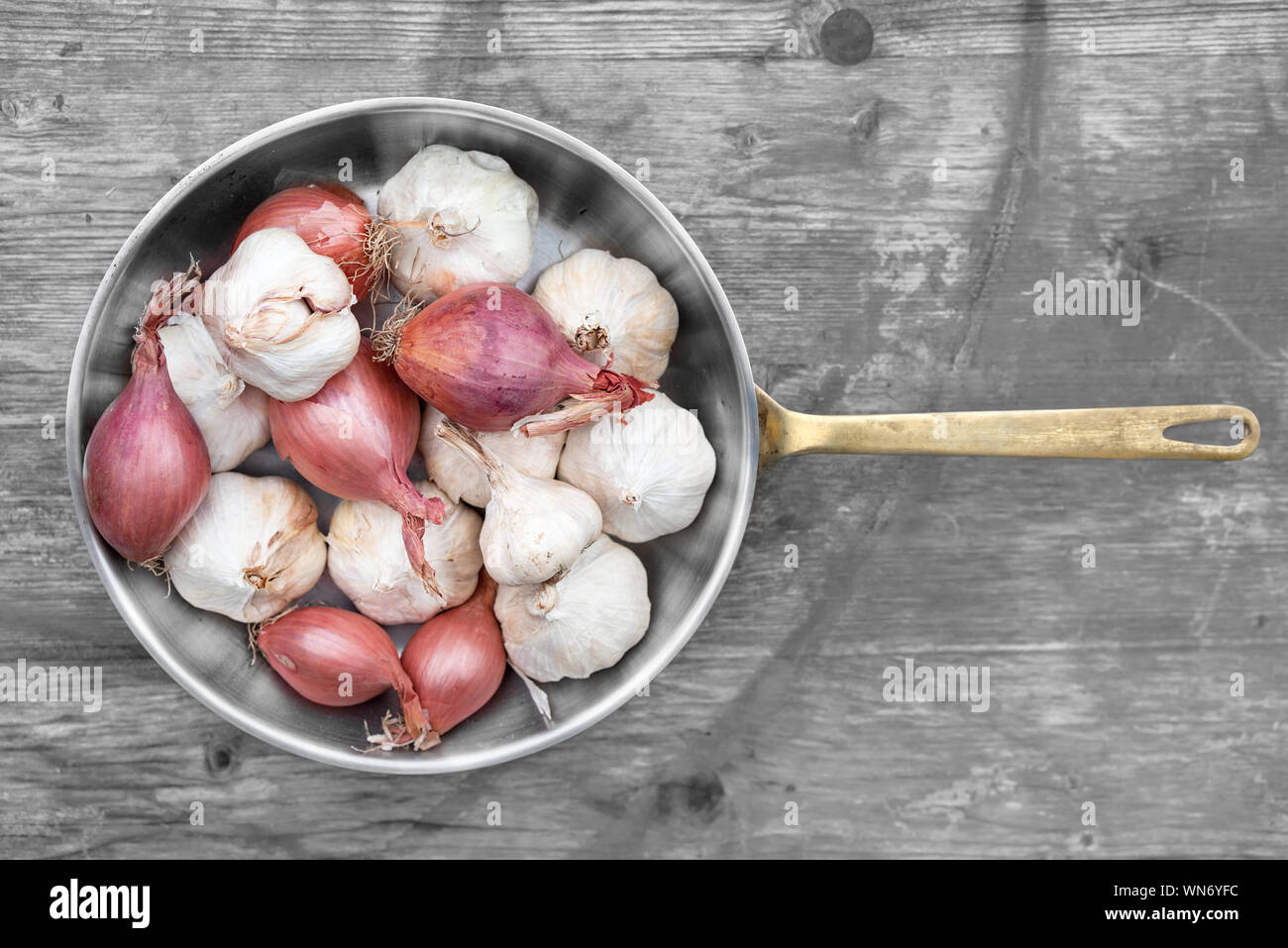 Directly Above View Of Onions And Garlic Cloves In Cooking Utensil On Table Stock Photo