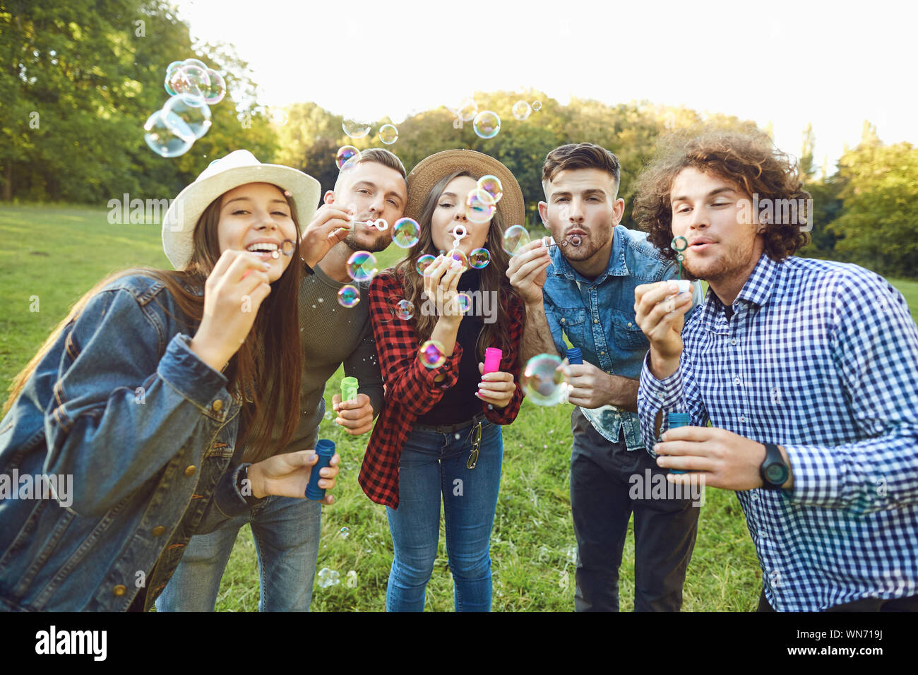 Young friends blowing soap bubbles in park Stock Photo