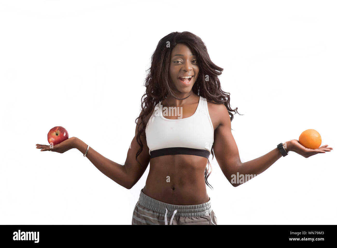 Portrait Of Happy Model Holding Apple And Orange Fruit Against White Background Stock Photo