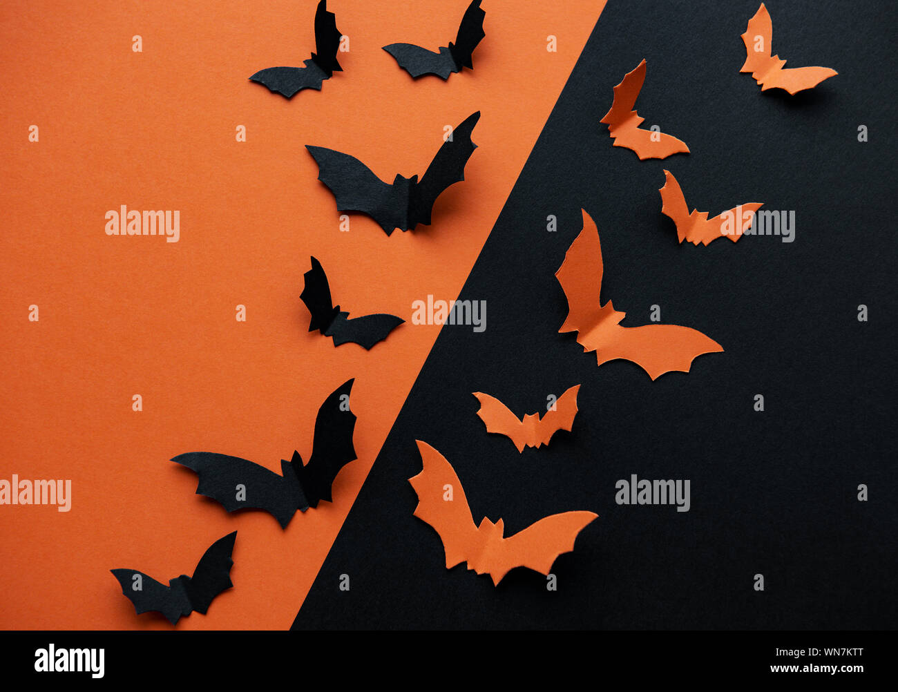 halloween concept - black and orange paper bats flying over black and ...