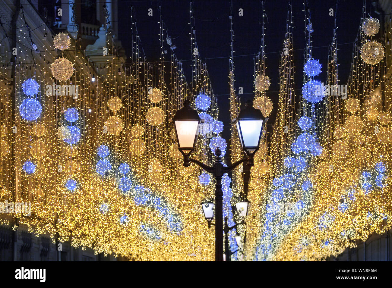 Many bright burning lights blue and yellow lanterns hanging on black