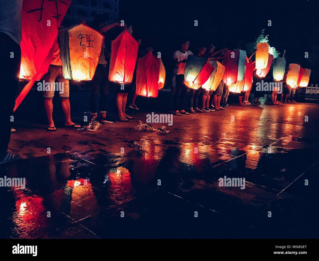 People Standing With Illuminated Paper Lanterns On Wet Footpath During  Tanabata Festival Stock Photo - Alamy