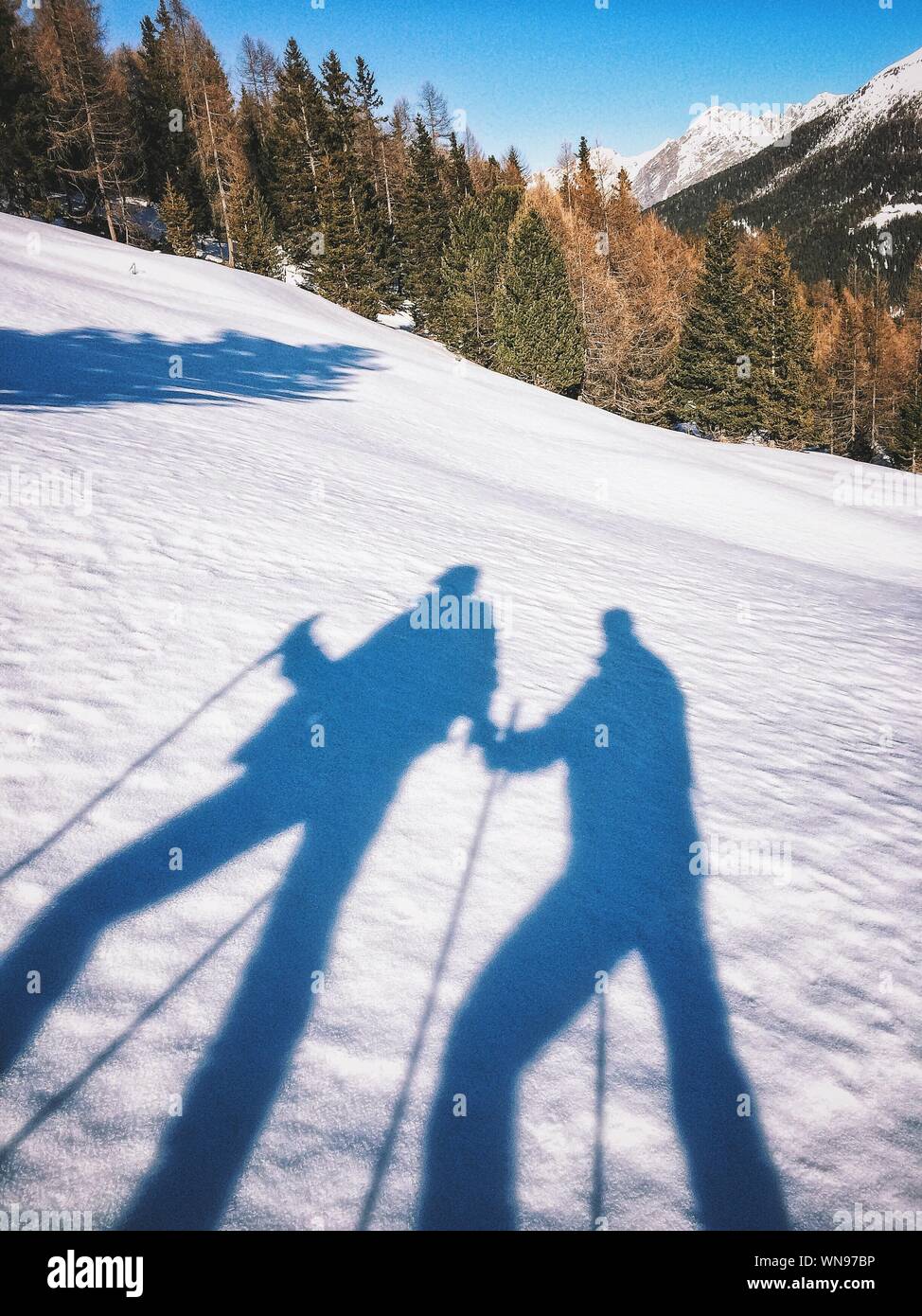 Shadow Of People Skiing On Snowcapped Mountain Stock Photo