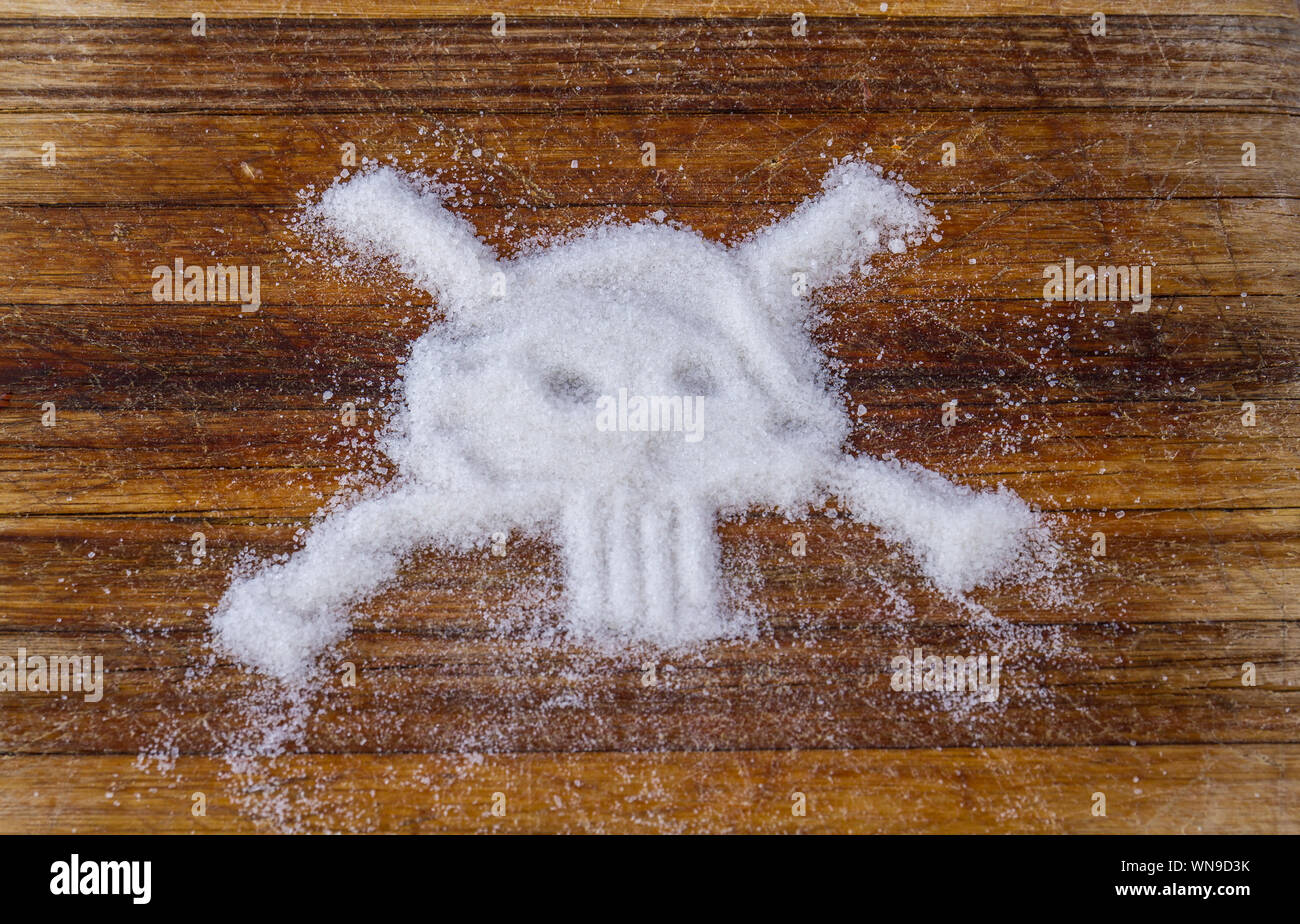 Refined white sugar shaped like a skull and crossbones isolated on a wood surface image with copy space in horizontal format Stock Photo