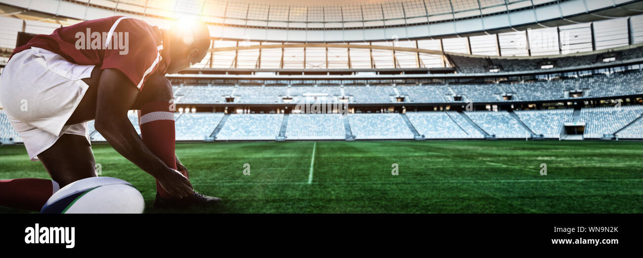 Composite image of african-american man tying shoelaces in rugby pitch Stock Photo