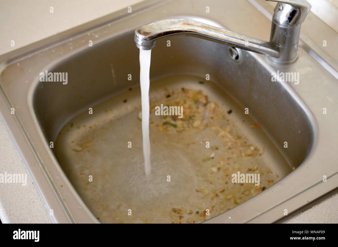 Stainless steel sink plug hole close up full of water and particles of