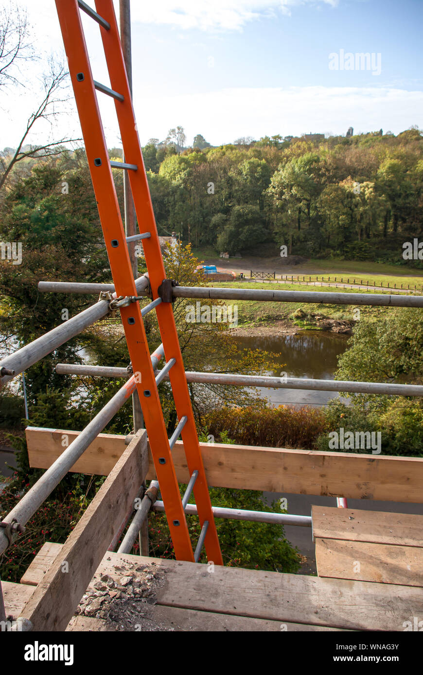 Orange scaffolding ladder through access hatch with view behind (portrait) Stock Photo