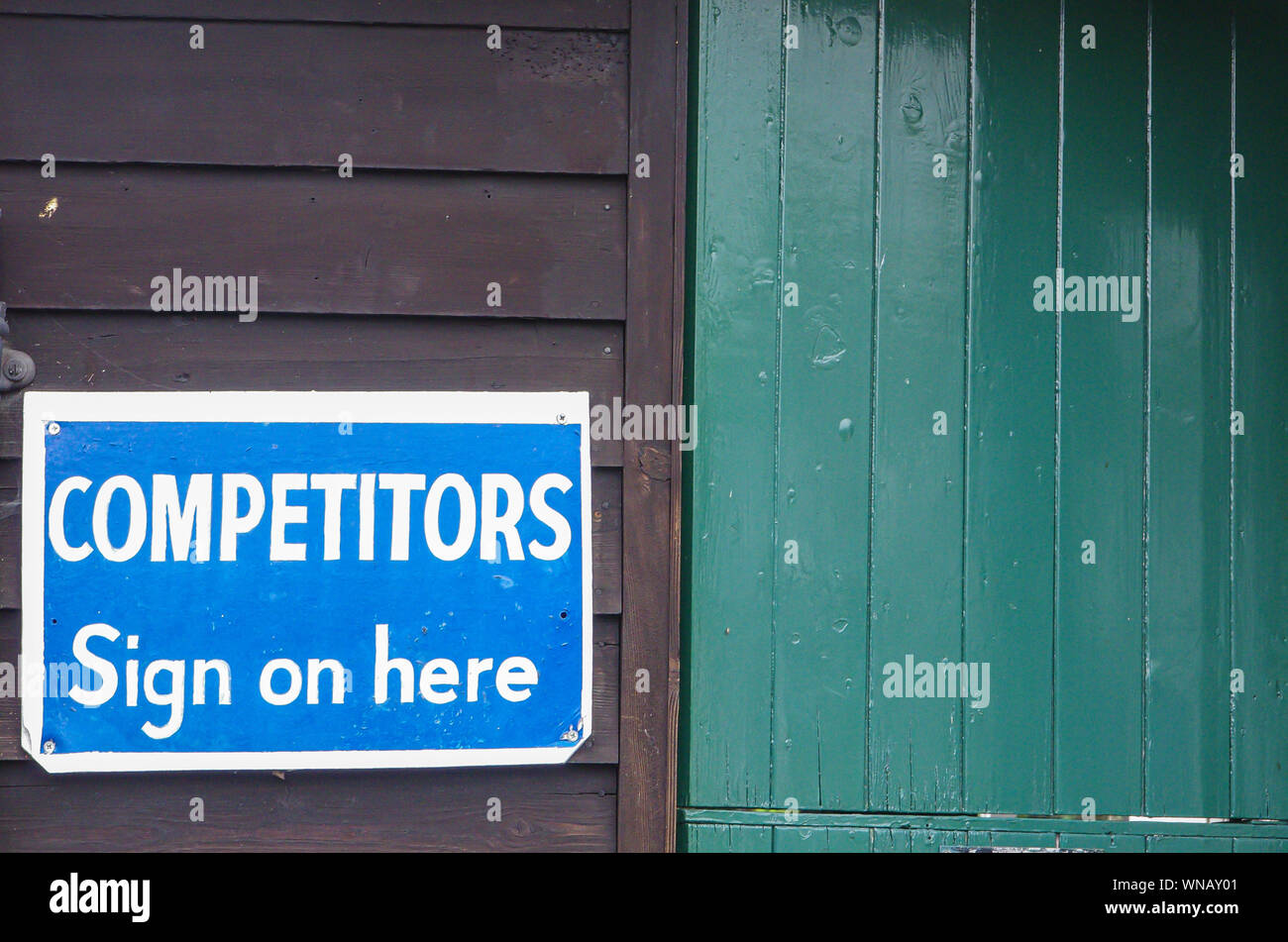 Competitors sign on here sign next to green wooden door Stock Photo