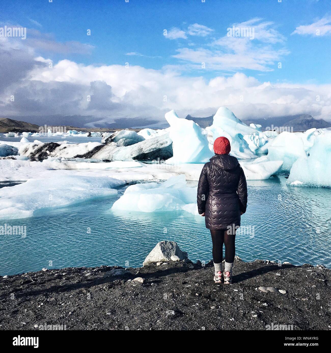 Rear View Of Woman Standing In Front Of Melting Glaciers Stock Photo