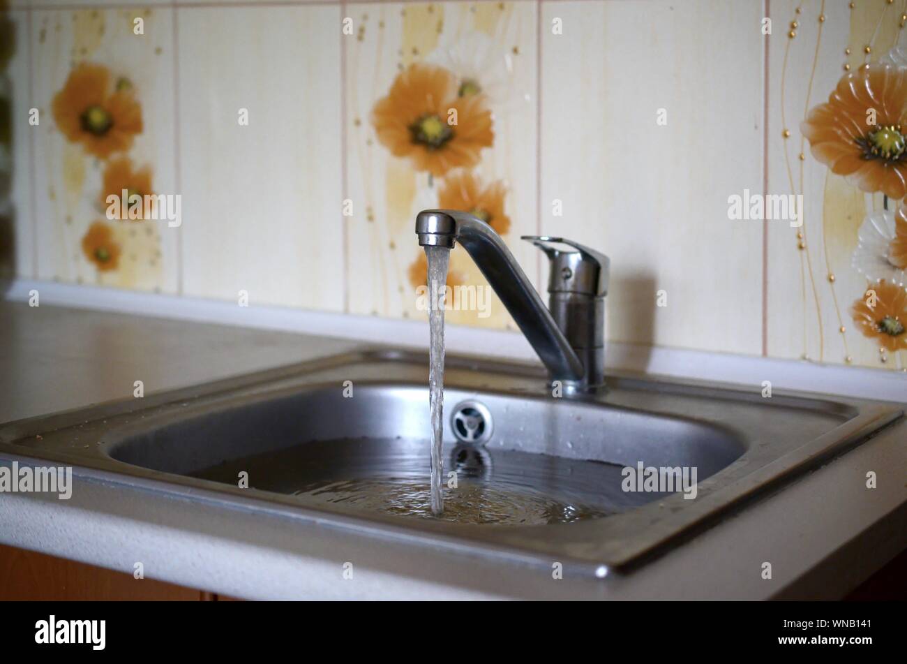 Stainless steel sink plug hole close up full of water and particles of