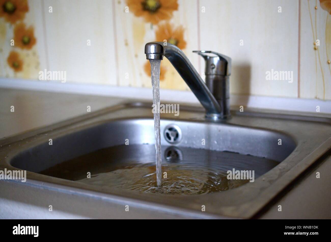 Stainless steel sink plug hole close up full of water and particles of