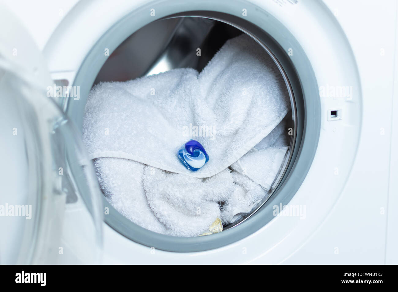 Washing gel in a washing machine. Colorful laundry eco gel in capsule