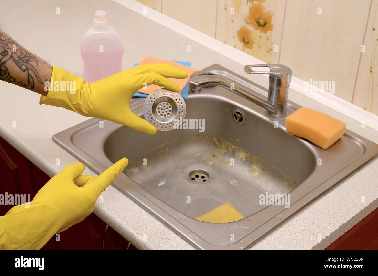 Cleaner in rubber gloves shows clean plughole protector of a