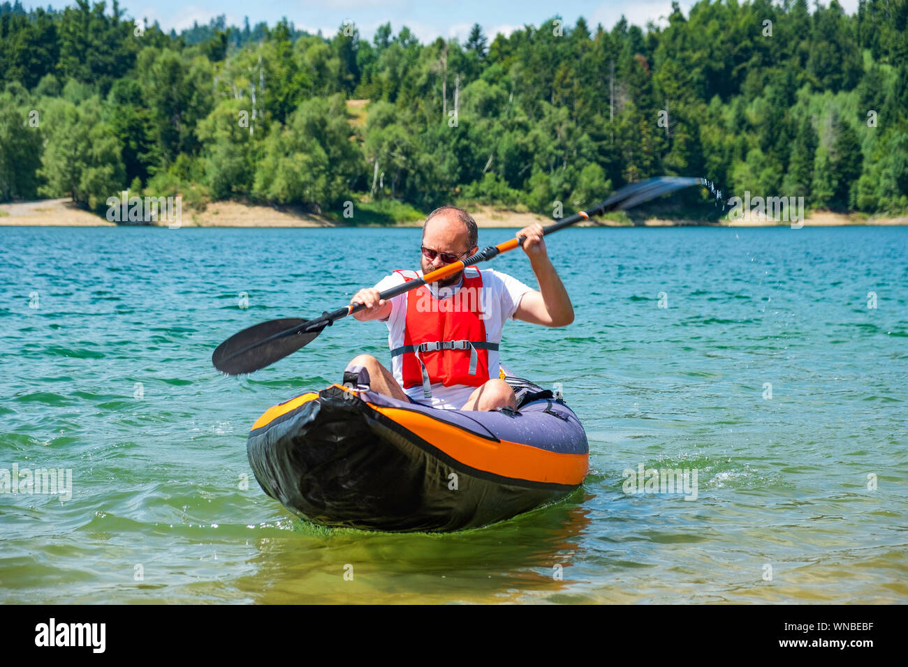 Man paddling in inflatable kayak on lake Lokve, in Gorski kotar, Croatia. Adventurous kayaking experience in a beautiful nature. Stock Photo