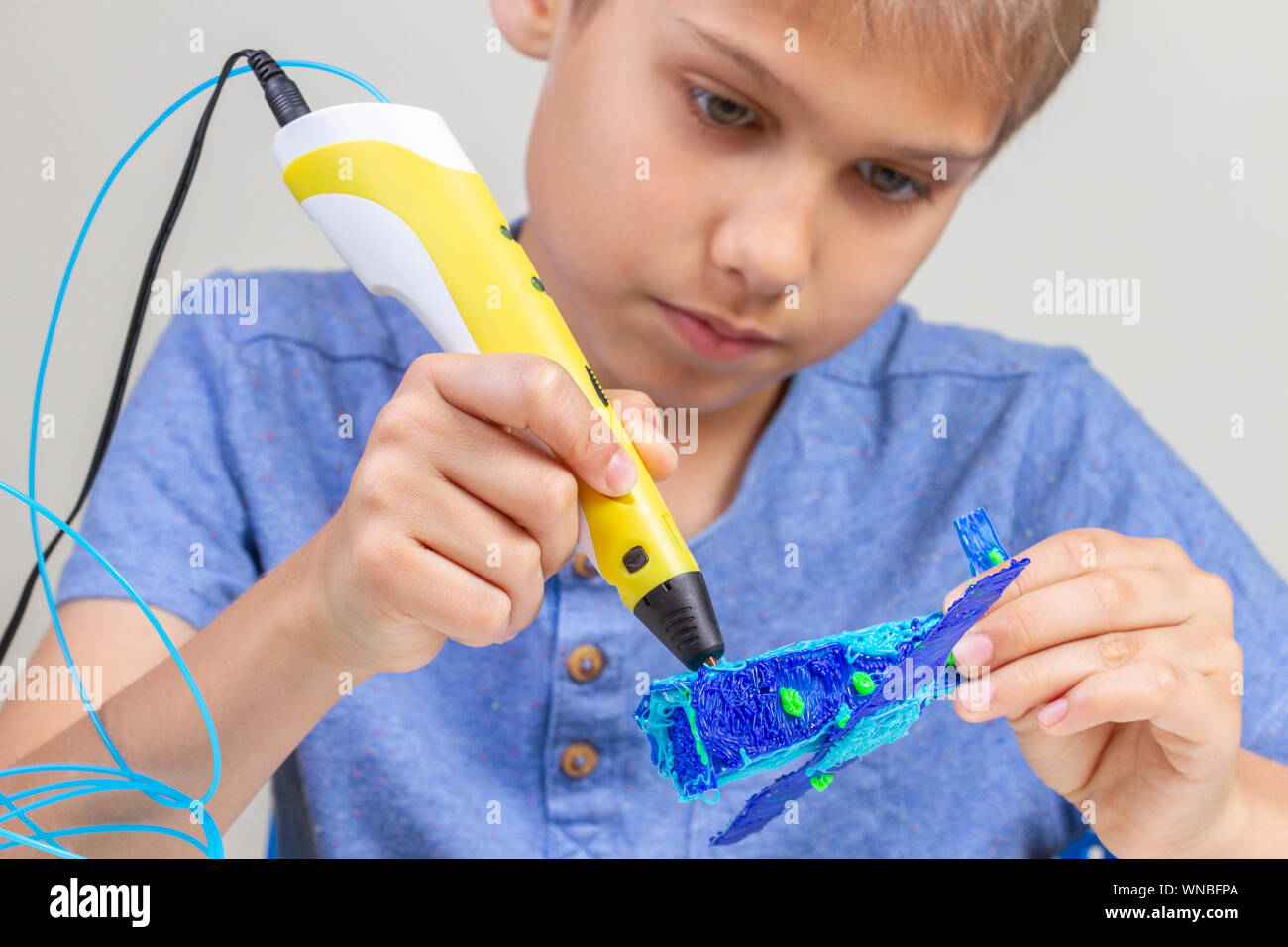 Boy hands creating with 3d pen blue plane Stock Photo - Alamy