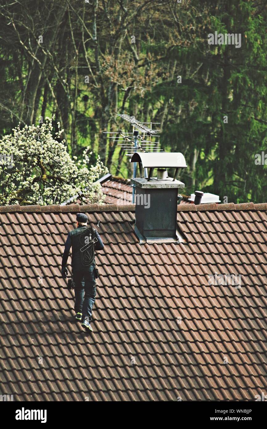 High Angle View Of Chimney Sweep Walking On Roof Stock Photo