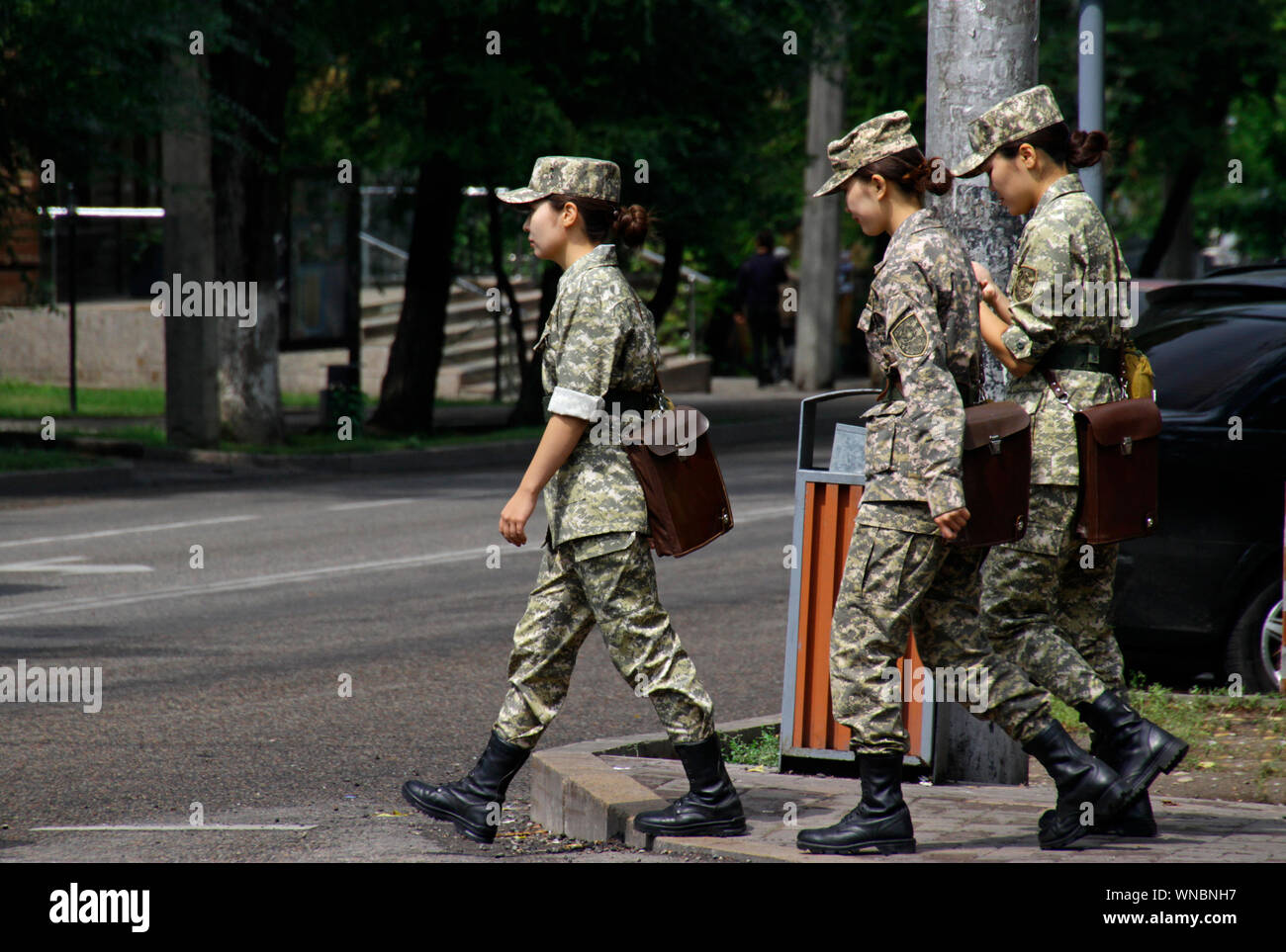 Almaty, Kazakhstan - August 24, 2019: Three women in uniform crossing a street in Almaty. Stock Photo