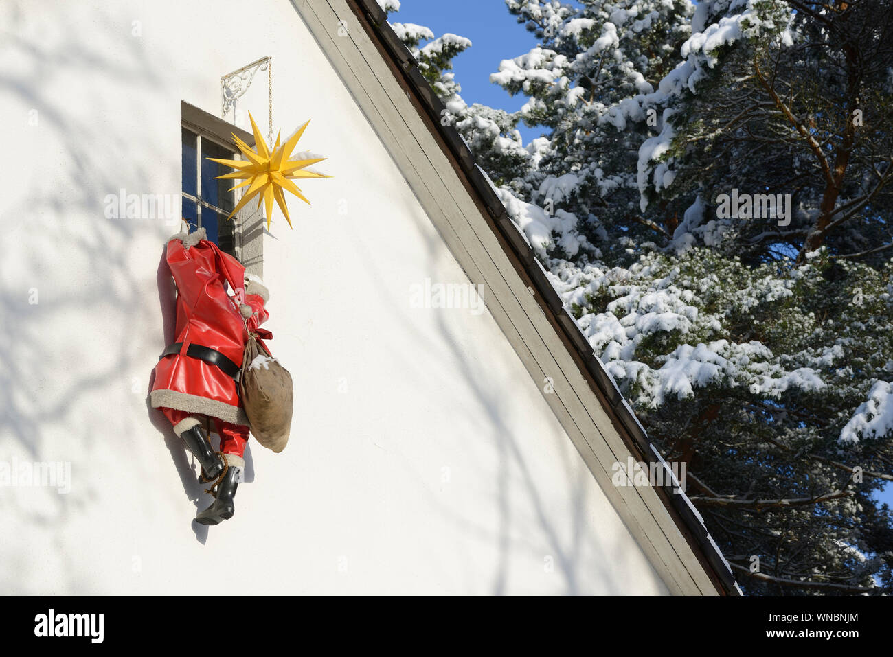 Housebreaker disguised as Santa Clause climbs up a house wall to break in a house through a window Stock Photo