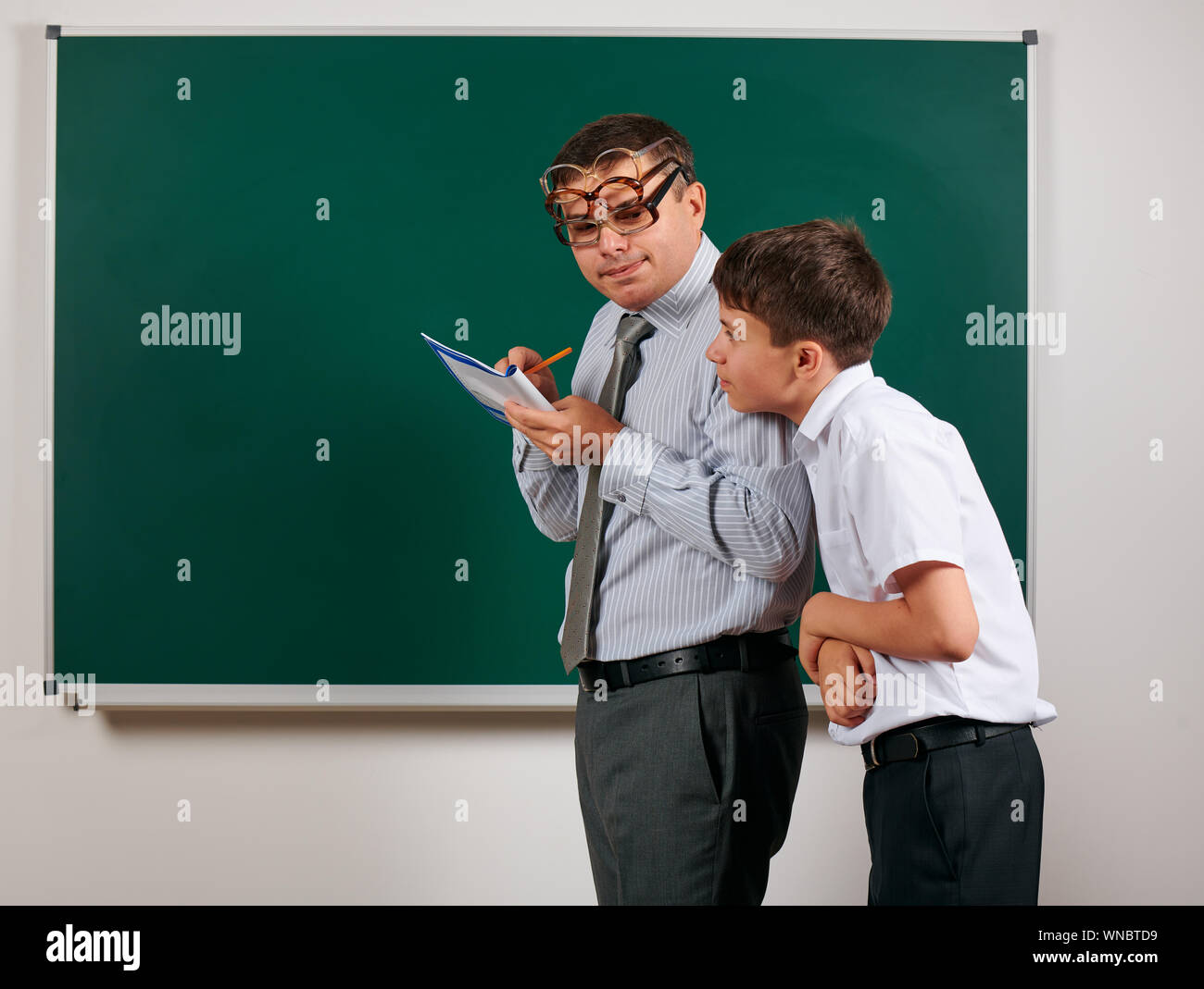 Portrait of a teacher checking homework, reading school exercise books ...