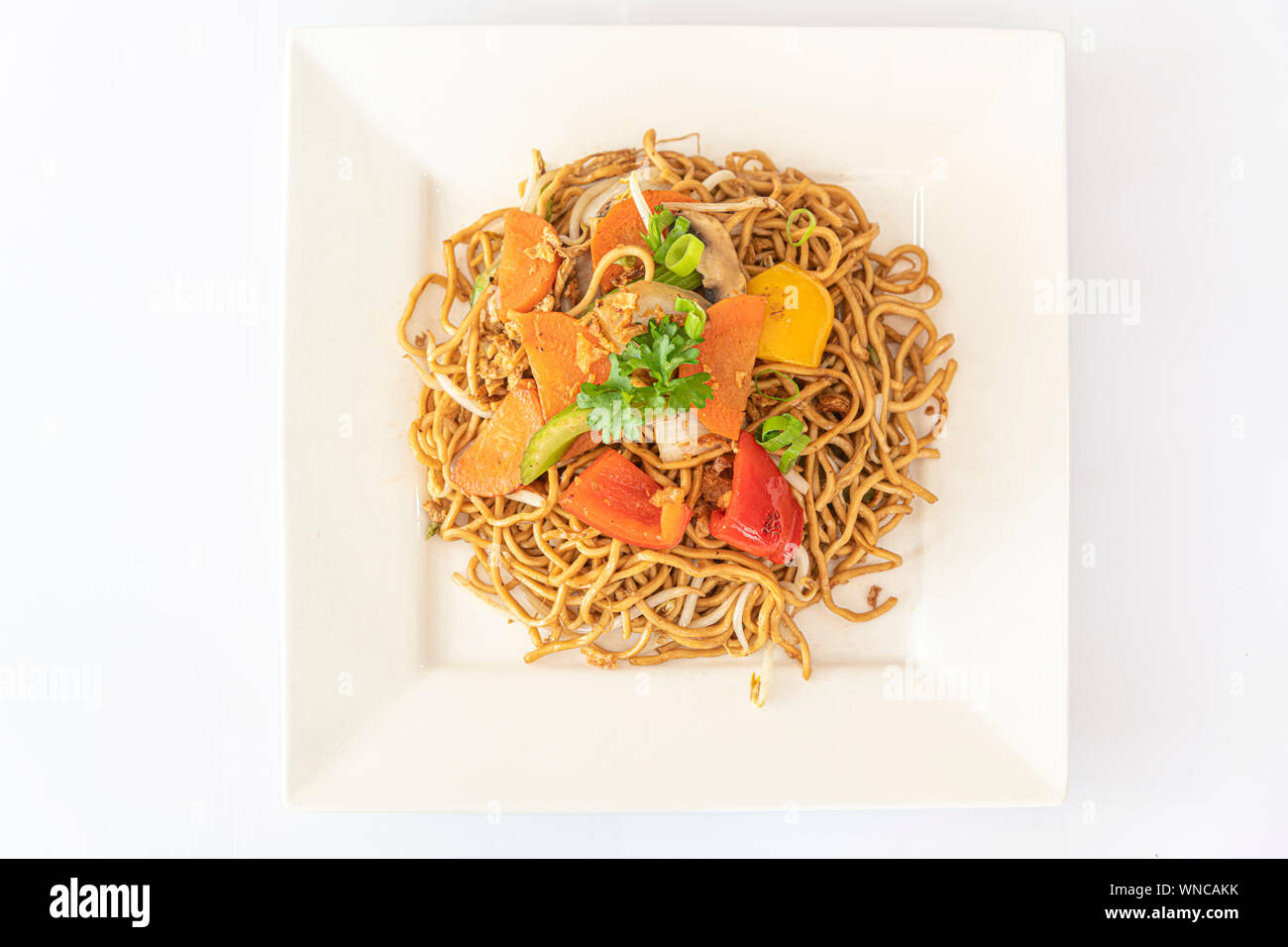 Chinese fried noodle server with fresh vegetable and on a square white plate Stock Photo