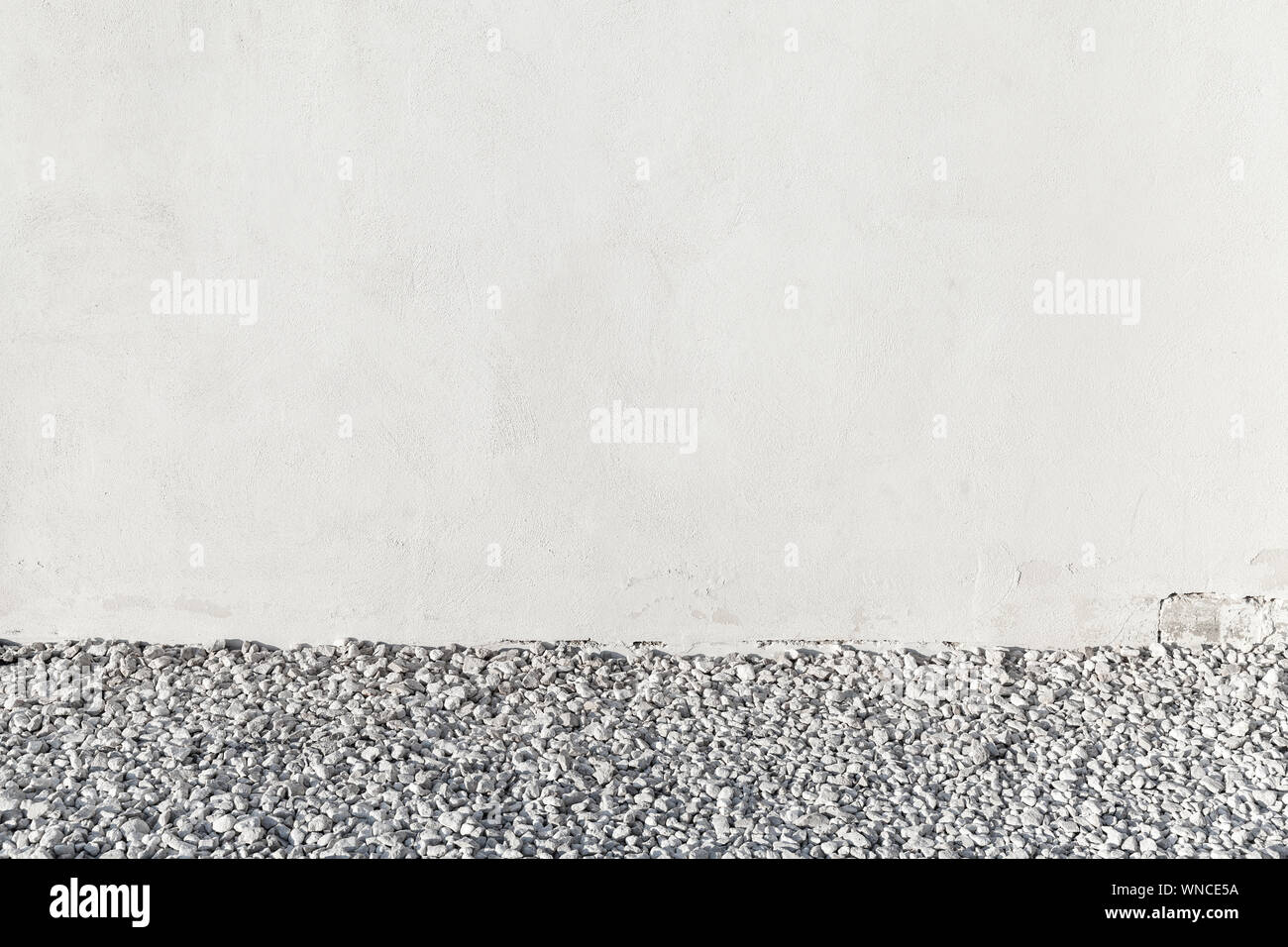 Empty white concrete wall and gravel, background photo texture Stock Photo