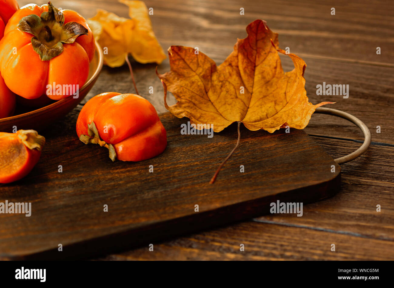 Ripe persimmons on a wooden background. Persimmon variety Fuyu. Close-up. Stock Photo