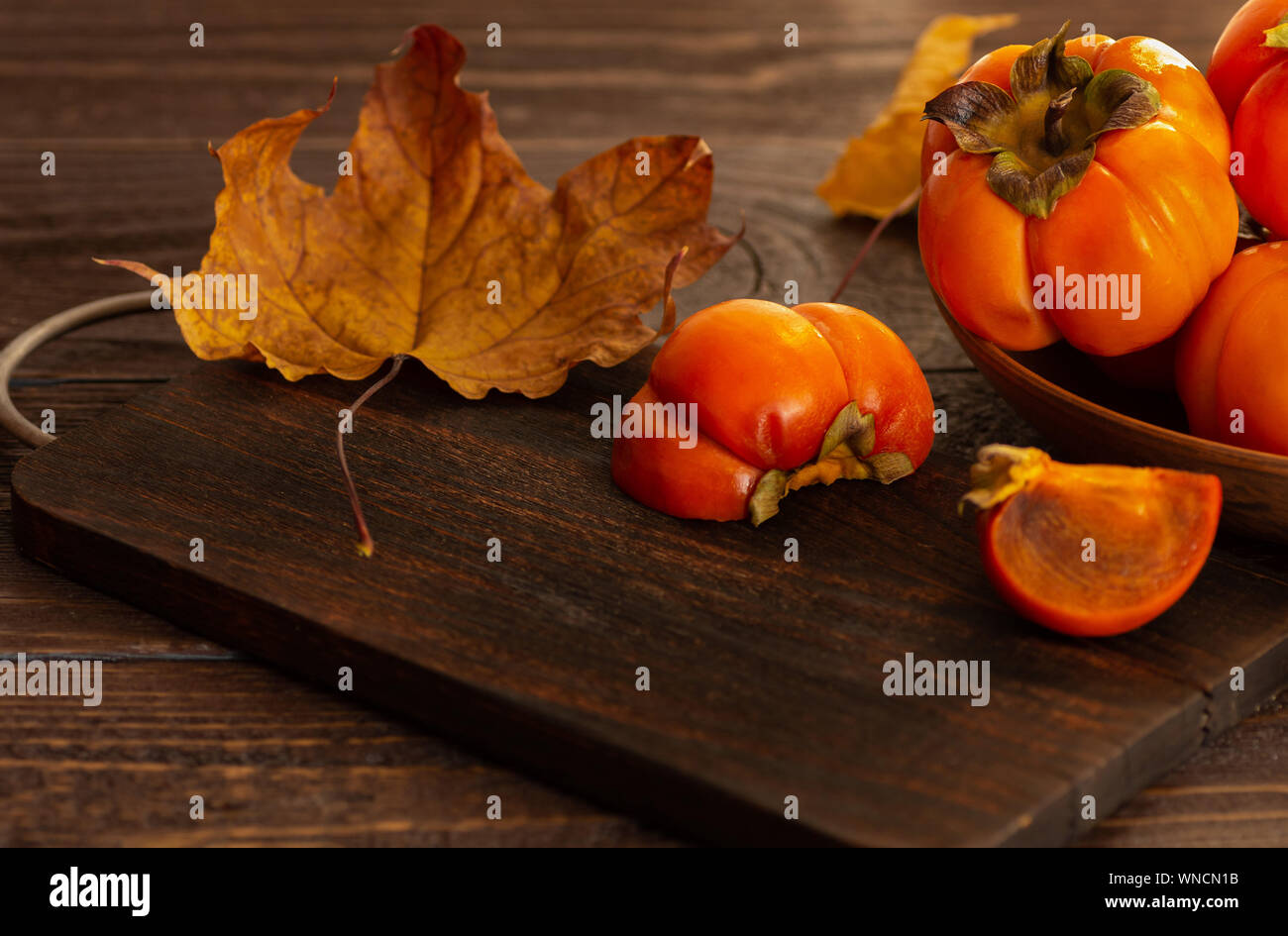 Ripe persimmons on a wooden background. Persimmon variety Fuyu. Close-up. Stock Photo