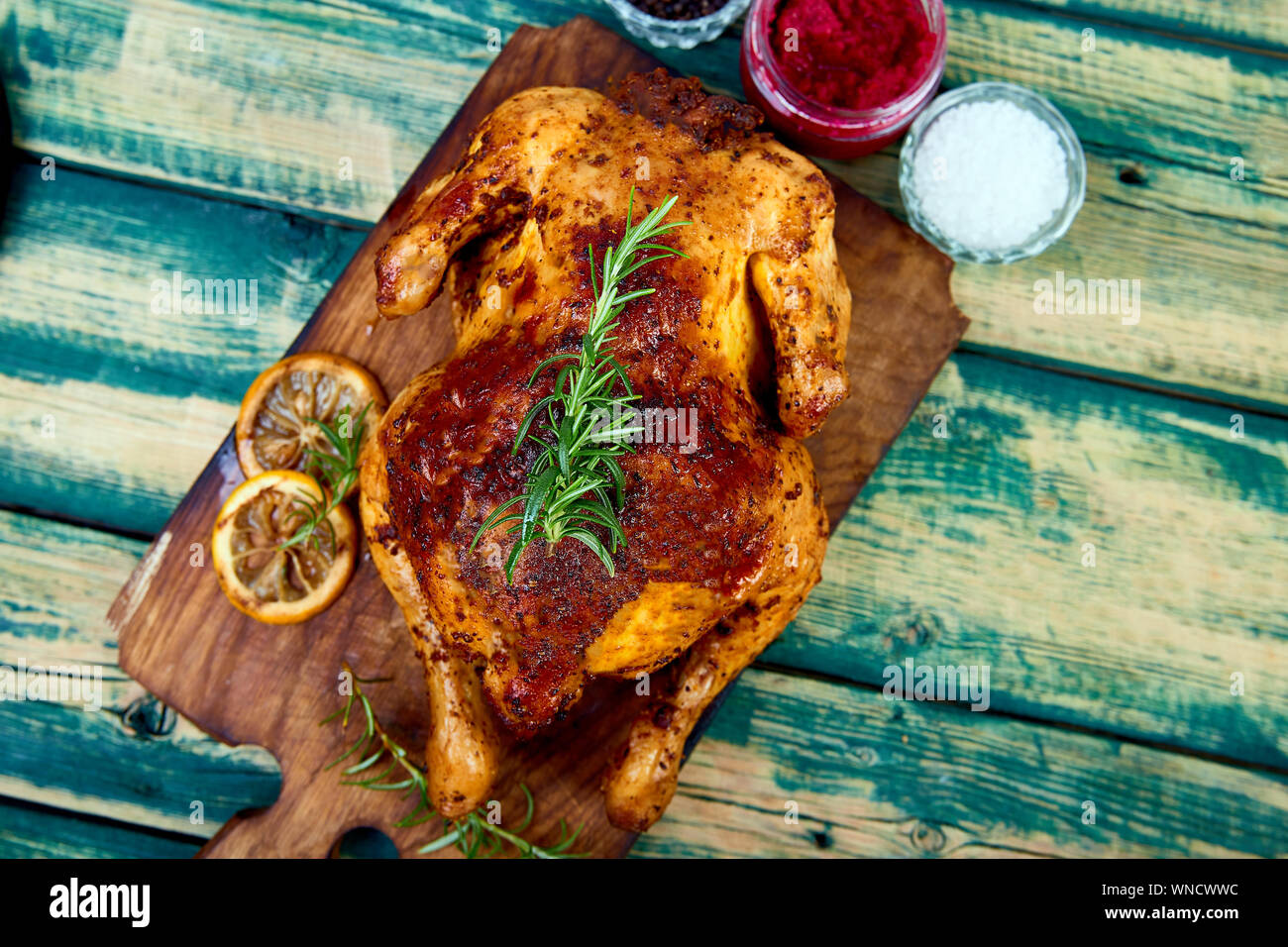 Baked whole chicken with sauces on wooden board on wooden green ...