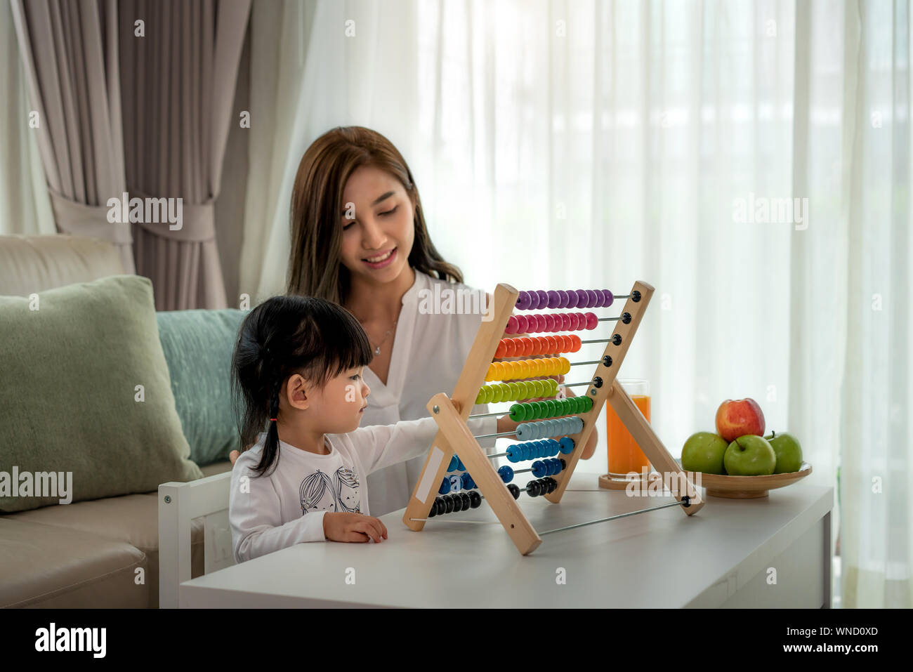 Happy Asian young mother and daughter playing with abacus, early education at home. Stock Photo