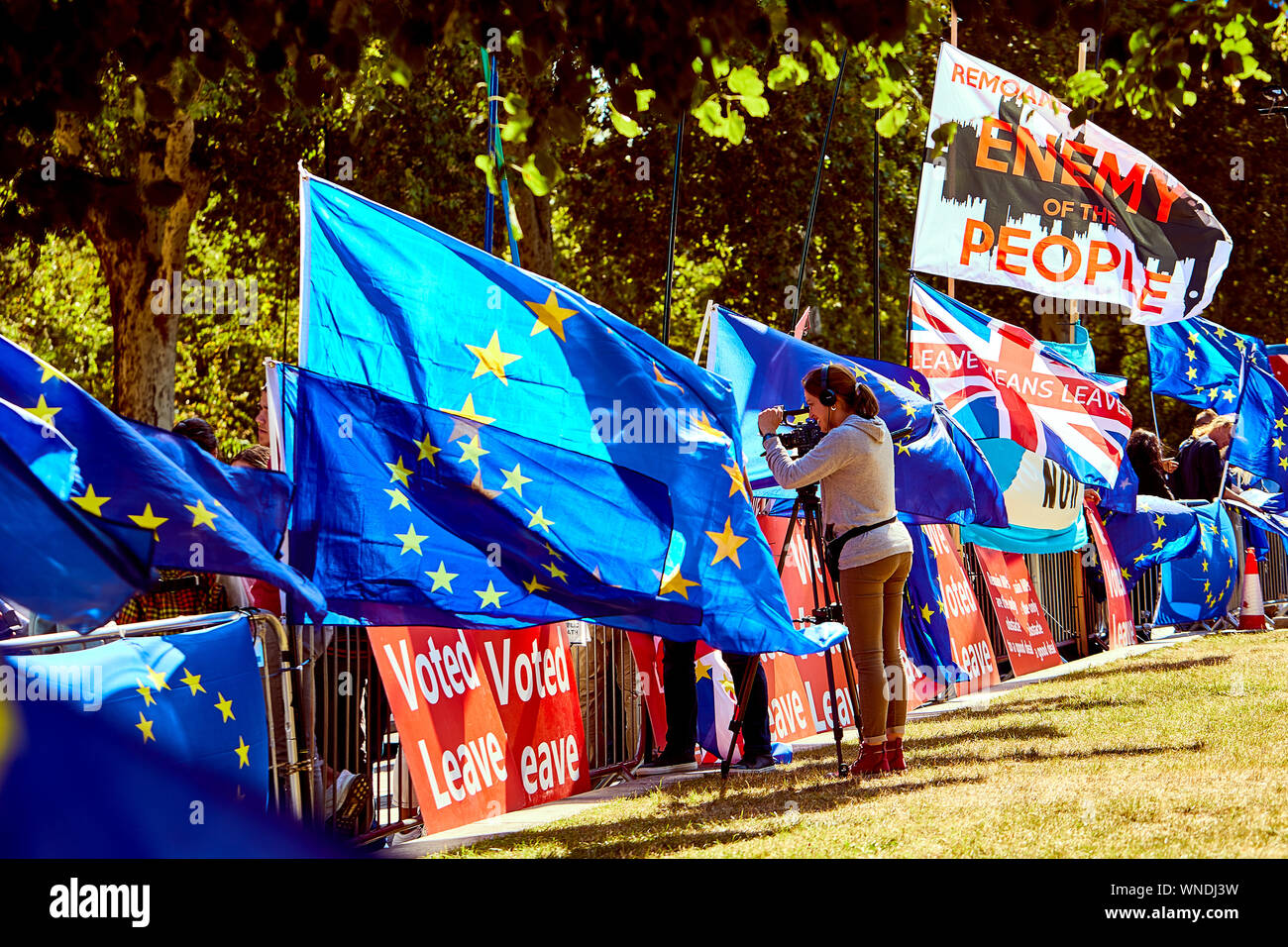 London, U.K. - September 5, 2019: A camera operator films protestors outside Parliament amongst flags and banners a month before the UK is due to leave the EU. Stock Photo