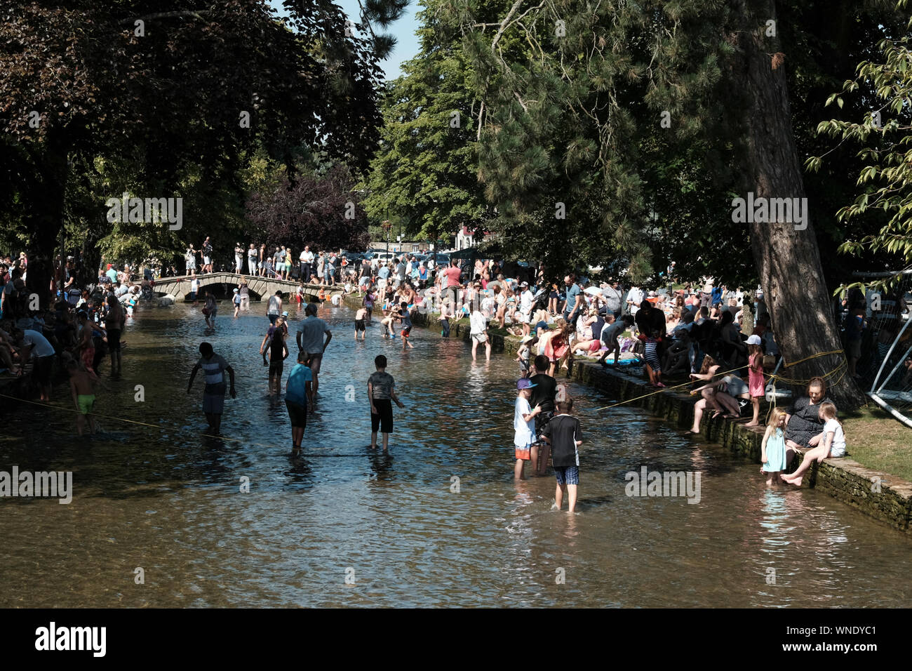 August Bank Holiday festivities in Bourton-on-the Water Gloucestershire UK. Paddling in the River. Stock Photo