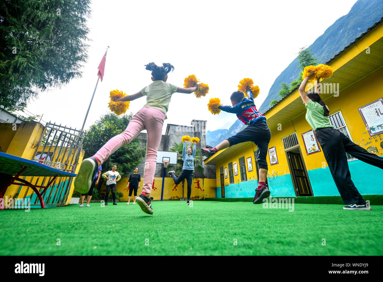 (190906) -- CHONGQING, Sept. 6, 2019 (Xinhua) -- Volunteer teacher Mu Yi (3rd R) teaches students aerobics at Lianhua Primary School of Luzi Village, Chengkou County, southwest China's Chongqing Municipality, Sept. 3, 2019. Mu Yi, a 25-year-old PE teacher from Chongqing Municipality, offers a week-long volunteer teaching service and works with a local teacher Tao Yao in this remote village. In the school where only two second-grade students and 18 preschool children study, Mu Yi and Tao Yao also do other jobs as principals, cleaners, cooks and repairwomen. Mu Yi teaches children sports, art an Stock Photo