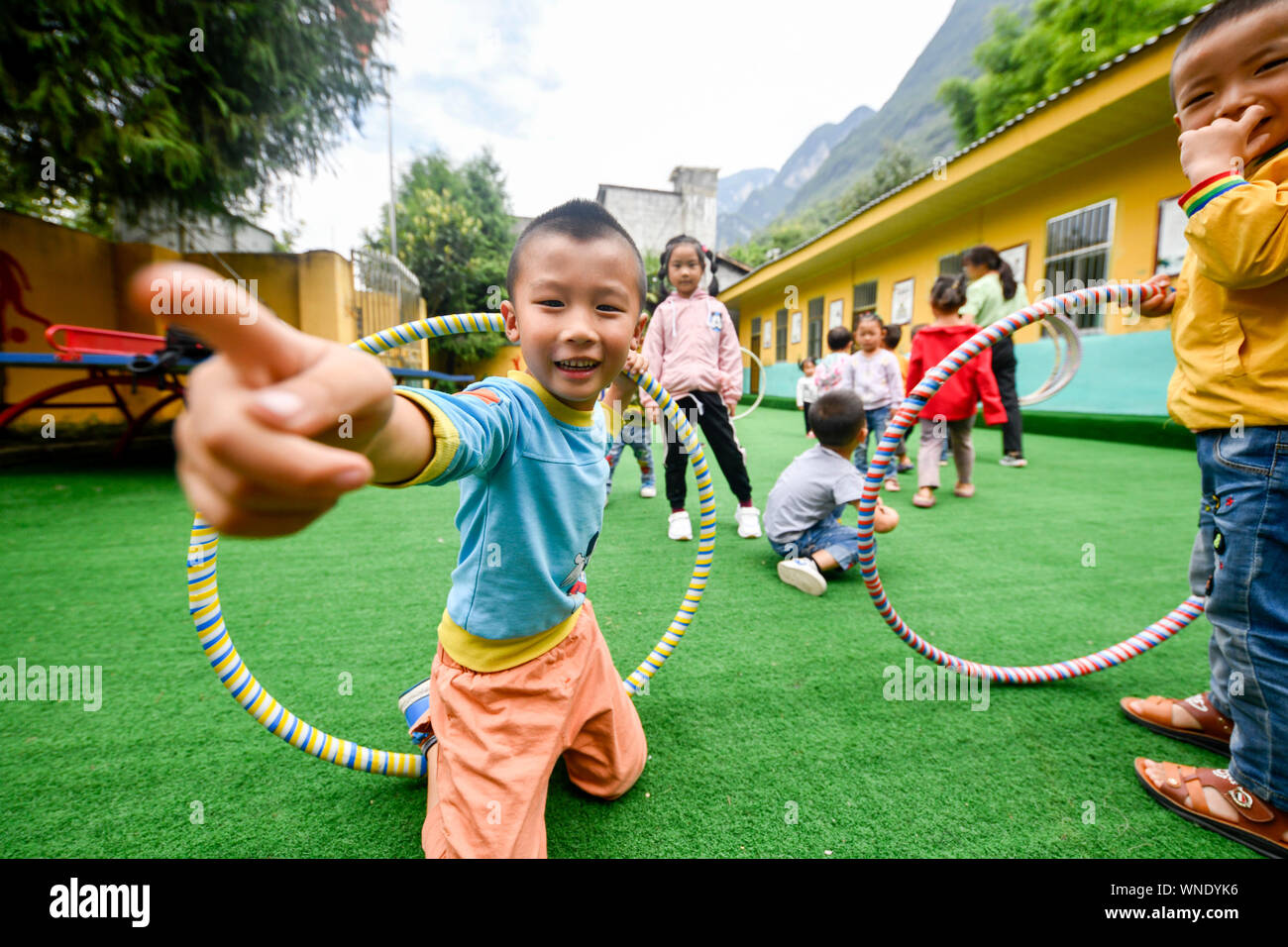 (190906) -- CHONGQING, Sept. 6, 2019 (Xinhua) -- Students enjoy a moment on the playground of Lianhua Primary School at Luzi Village, Chengkou County, southwest China's Chongqing Municipality, Sept. 3, 2019. Mu Yi, a 25-year-old PE teacher from Chongqing Municipality, offers a week-long volunteer teaching service and works with a local teacher Tao Yao in this remote village. In the school where only two second-grade students and 18 preschool children study, Mu Yi and Tao Yao also do other jobs as principals, cleaners, cooks and repairwomen. Mu Yi teaches children sports, art and music and tell Stock Photo