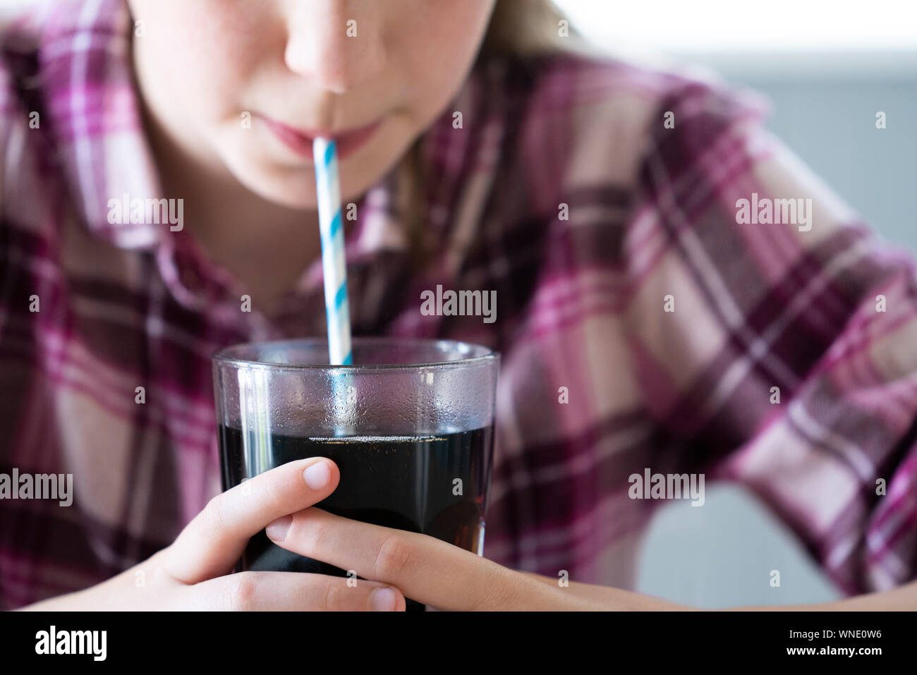 Close Up Of Girl Drinking Sugary Fizzy Soda From Glass With Straw Stock Photo