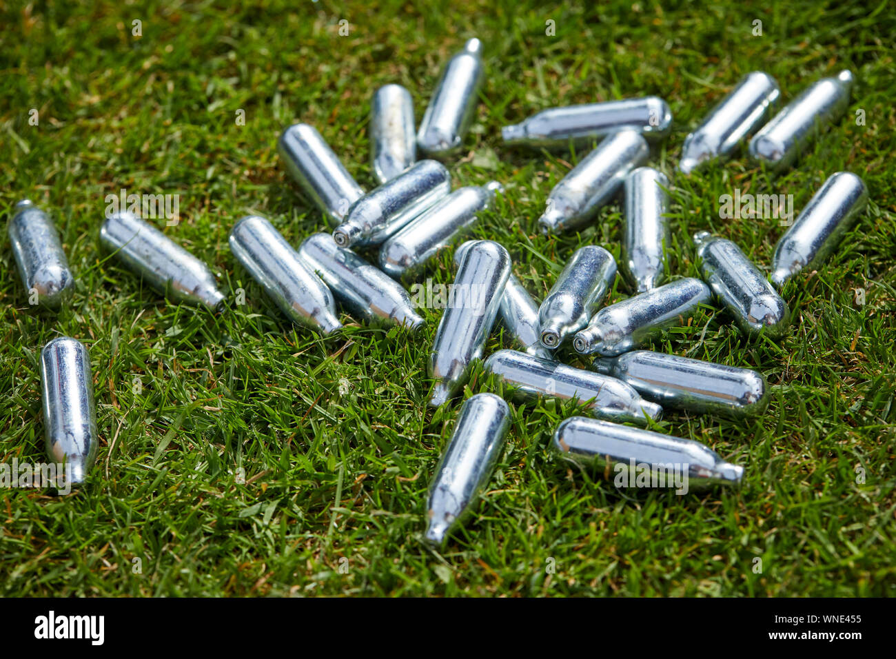 Discarded canisters of  NITROUS oxide, laughing gas or 'hippy crack metal canisters littering the streets. A colourless gas that people inhale, illega Stock Photo