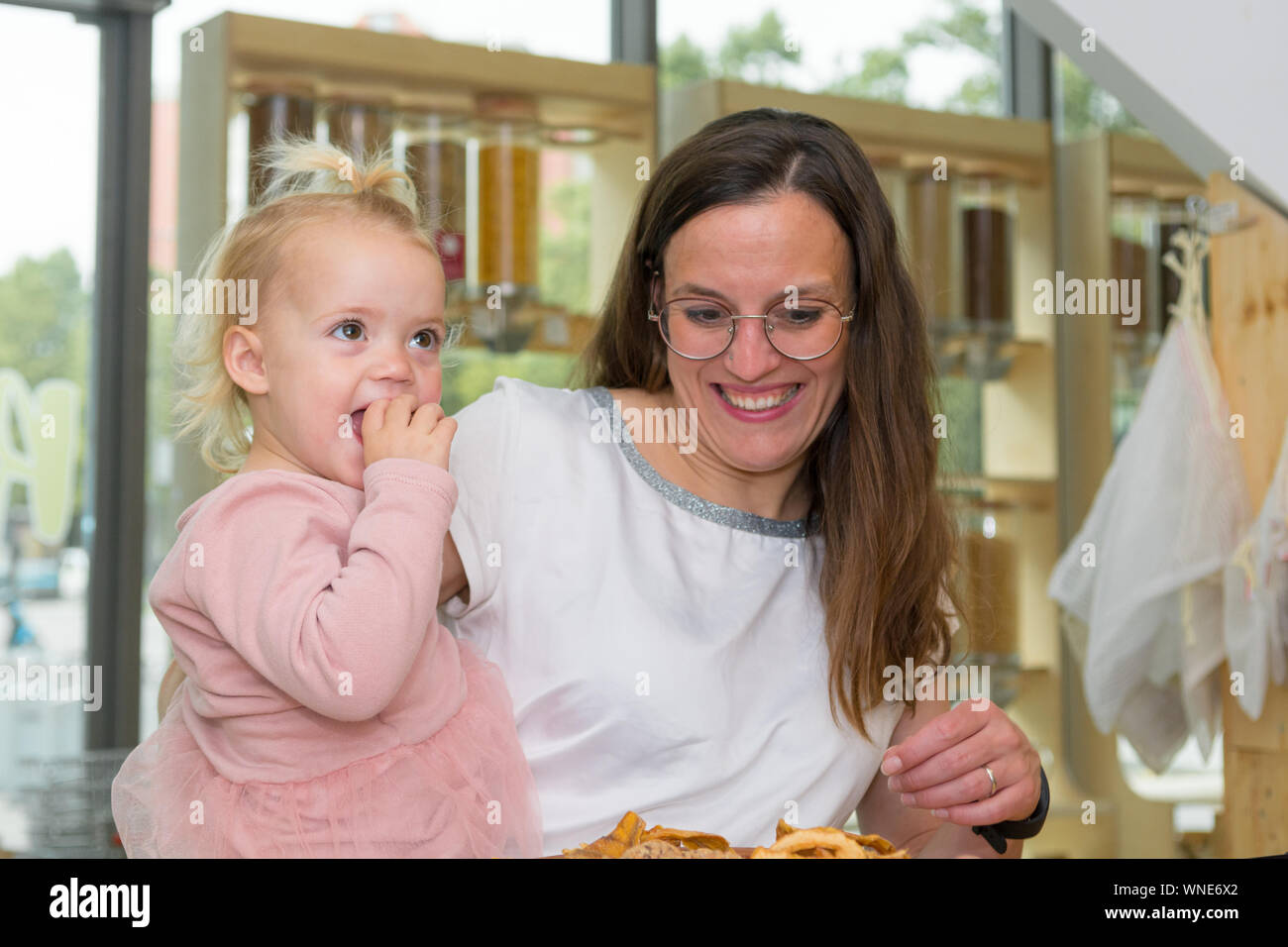 Cute adorable girl trying cookies at organic store with her mother.Degustaion of healthy desert. Stock Photo