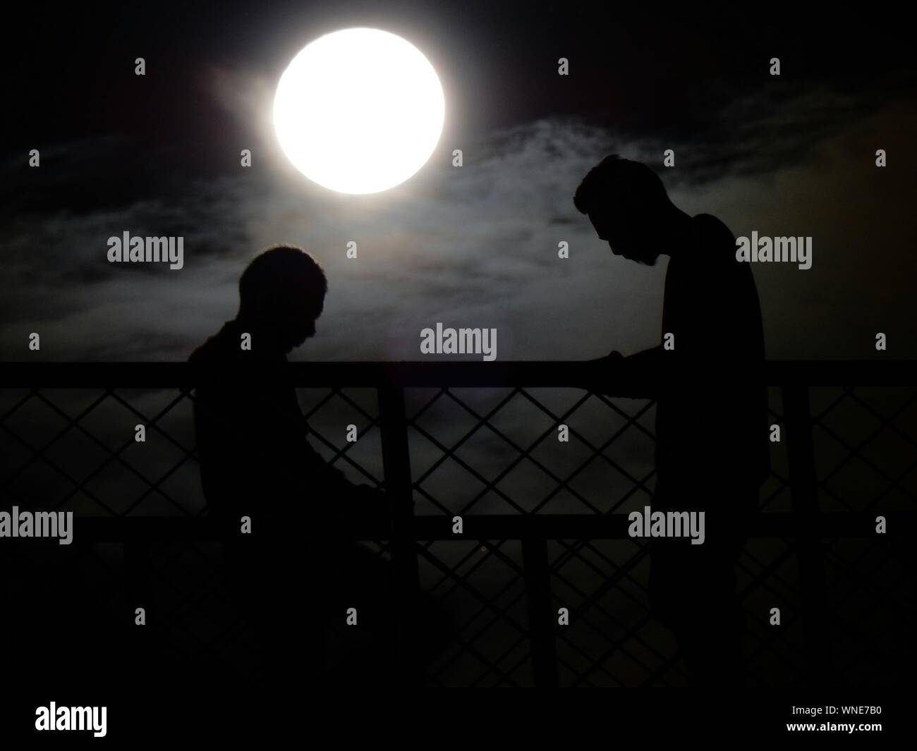 Side View Of Silhouette Friends Standing By Fence Against Full Moon At Night Stock Photo Alamy