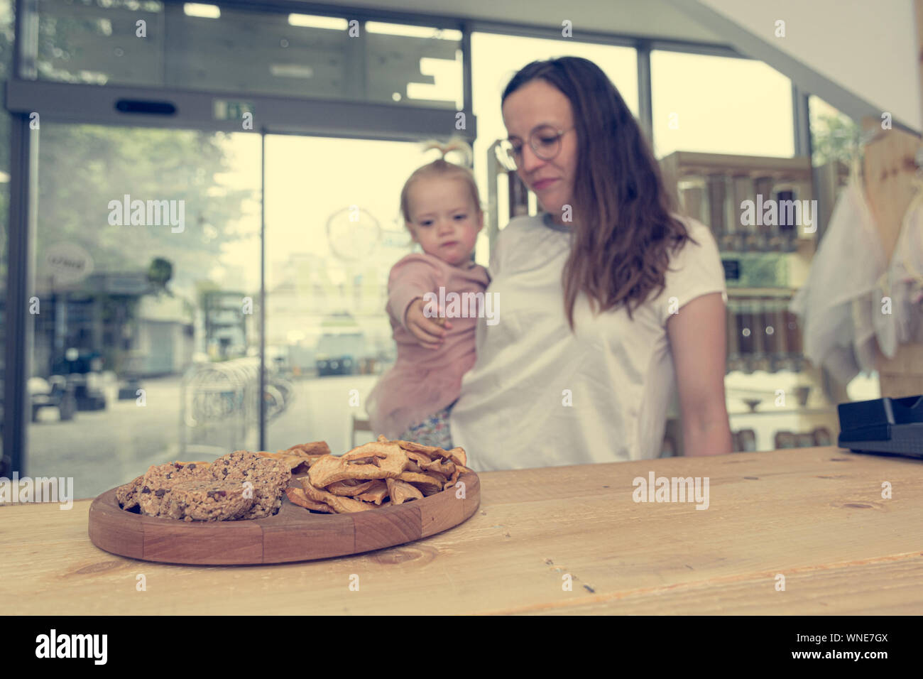 Cute adorable girl trying cookies at organic store with her mother.Degustaion of healthy desert. Stock Photo