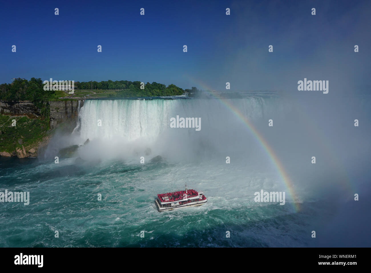 Niagara Falls, Ontario, Canada: A double rainbow appears over the Niagara River as a tour boat takes visitors to the foot of the Horseshoe Falls. Stock Photo