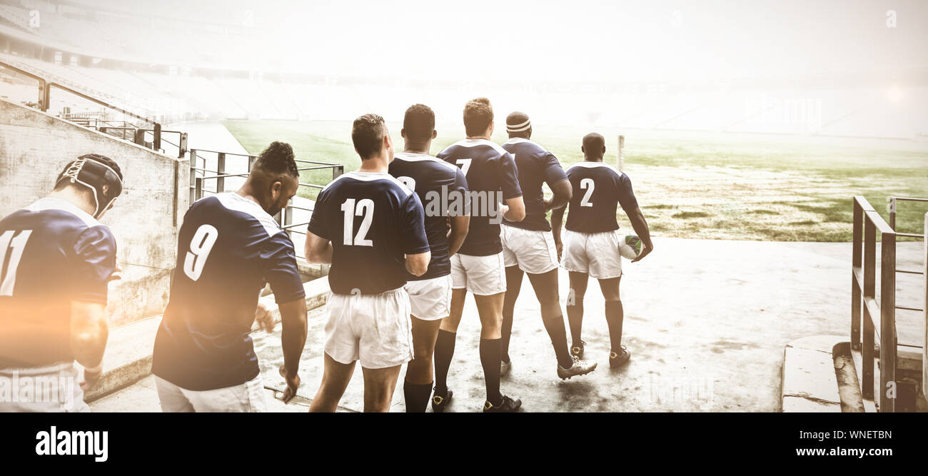 Diverse male rugby players standing at the entrance of stadium in a row ...