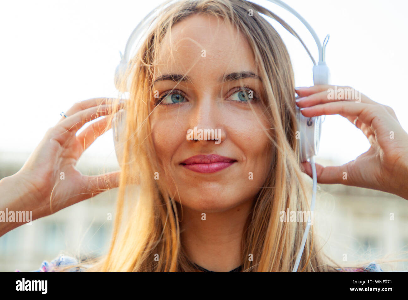 Beautiful young blonde woman with long hair and blue eyes listening to ...