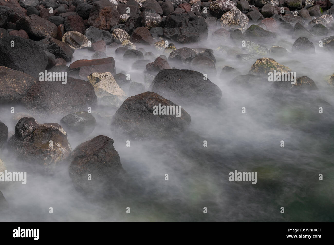 Big  volcanic coast rocks, with waves silky foam movement, long exposure photography, with sunset light, Atlantic ocean, Canary islands, Spain Stock Photo