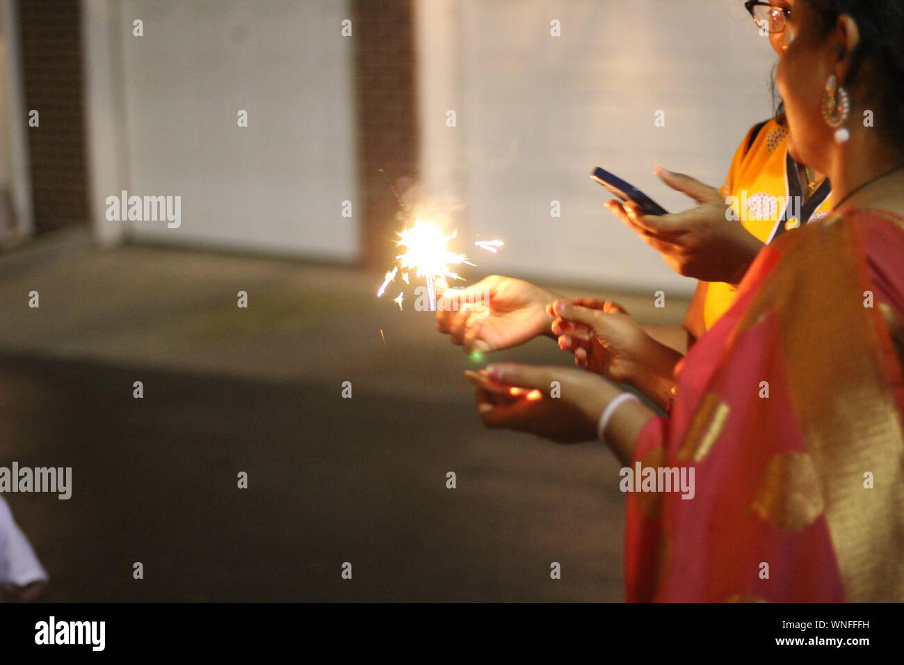 Side View Of Mid Adult Woman Burning Sparklers Stock Photo