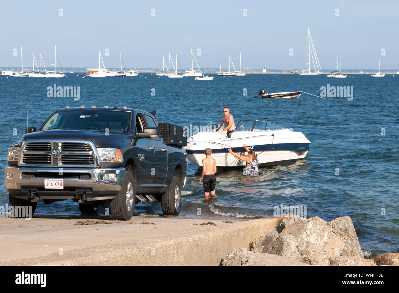Family of three hitching their boat, in the water, to their truck. Stock Photo