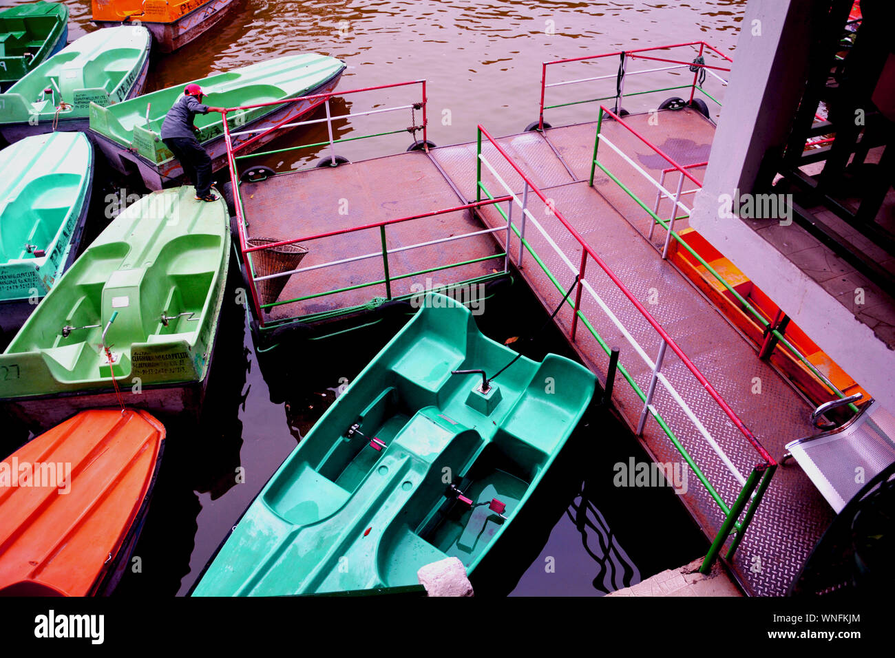 Colorful pedal boats in a lake in ward’s lake and the steel platform of the dock with railing Stock Photo